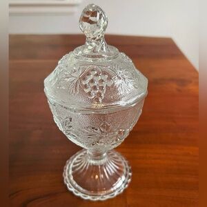 Clear glass candy dish with lid. Stands 7.5 inches tall. Very cute grape pattern